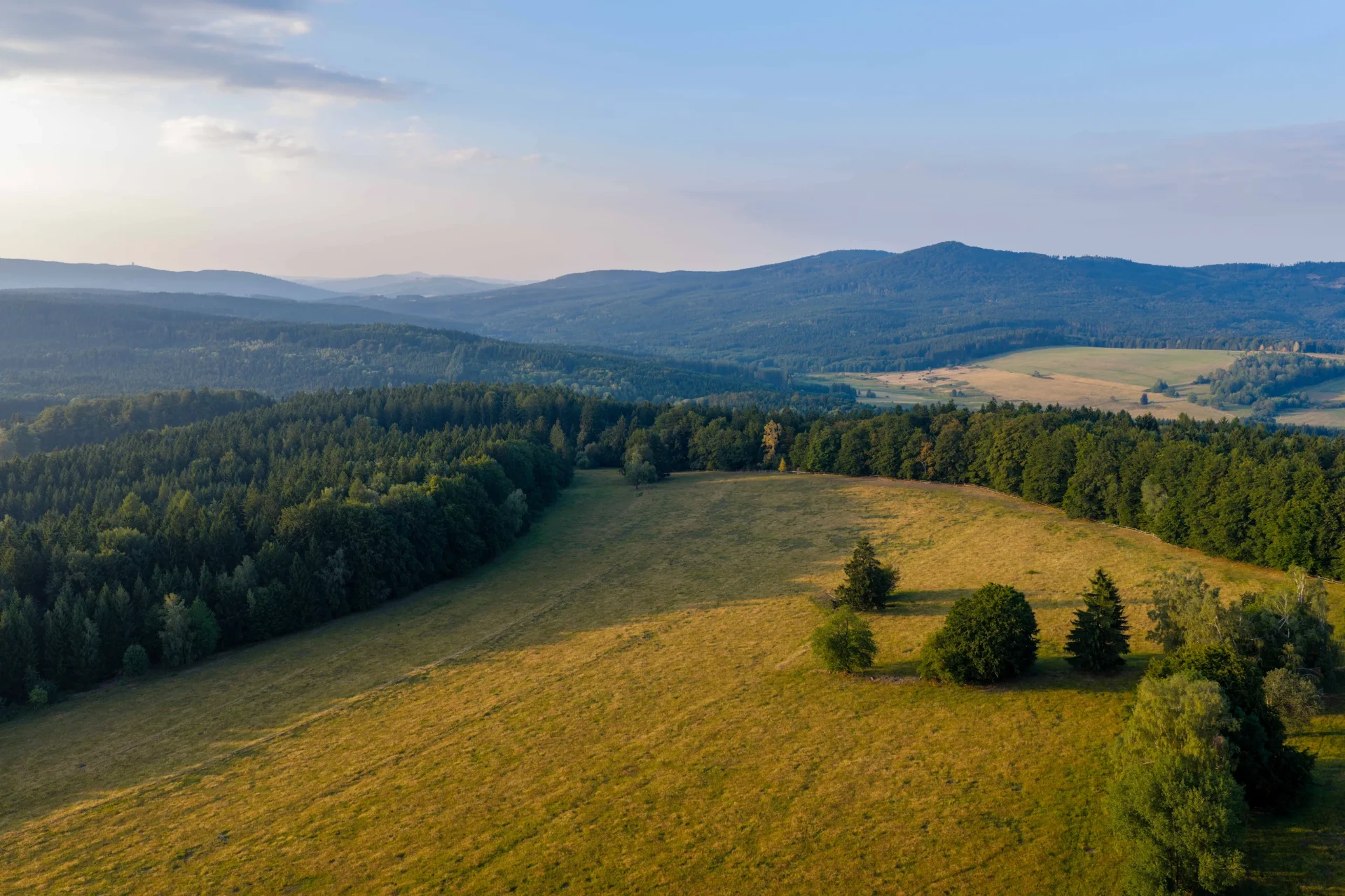 Evening light over meadows and forest in Český les